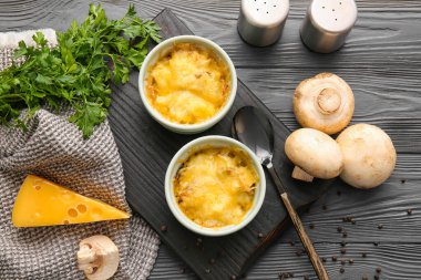 Ramekins with tasty julienne and ingredients on dark wooden background