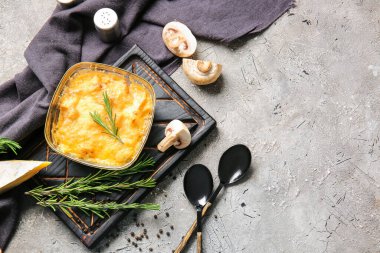 Baking dish with tasty julienne and ingredients on grey background