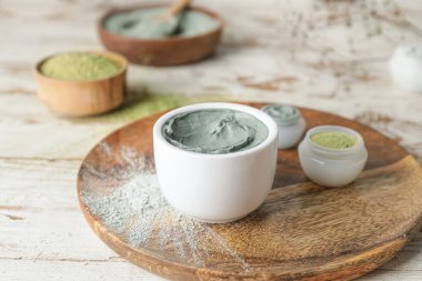 Plate with different cosmetic clay on light wooden background