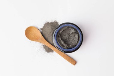 Jar and spoon with cosmetic clay on white background