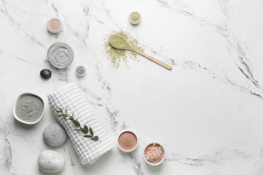 Composition with cosmetic clay, towel and spa stones on light background