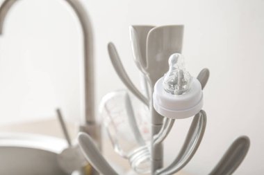 Drying rack for baby bottles on table near sink, closeup