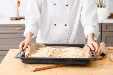 Woman with uncooked croissants in kitchen