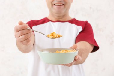 Senior man and bowl with cornflakes on white background