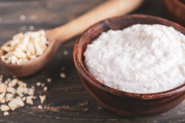 Bowl of sour cream with cashew nuts on dark wooden background, closeup