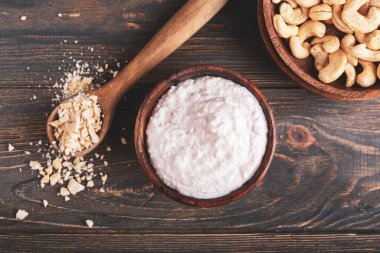 Bowl of sour cream with cashew nuts on dark wooden background