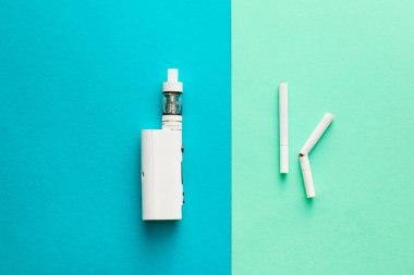 Vape mod with cigarettes on color background