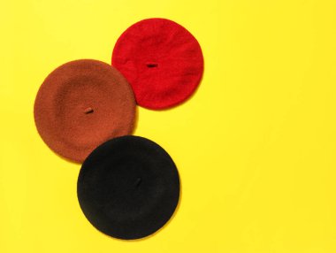 Stylish berets on color background