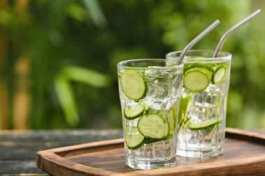 Glasses of cucumber lemonade on table outdoors