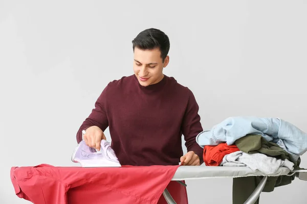 Joven Guapo Planchando Ropa Sobre Fondo Claro —  Fotos de Stock