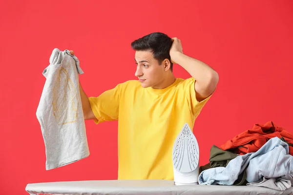 Αναστατωμένος Νεαρός Άνδρας Σιδέρωμα Ρούχα Στο Φόντο Χρώμα — Φωτογραφία Αρχείου
