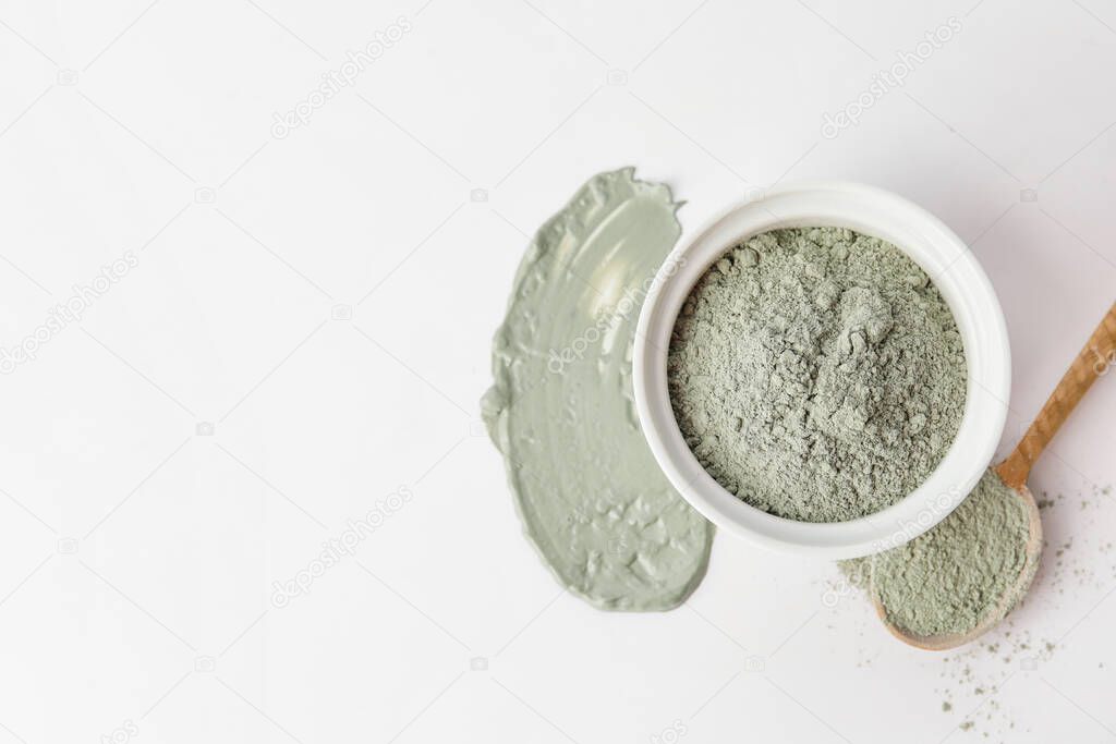 Bowl and spoon with cosmetic clay on white background