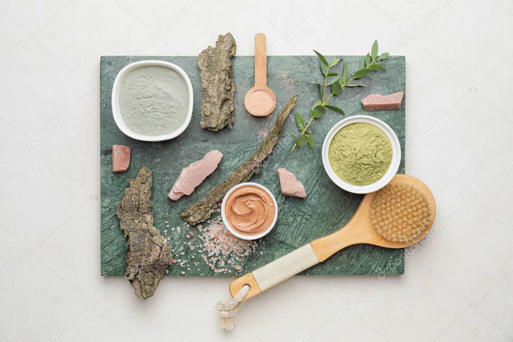 Composition with cosmetic clay and massage brush on light background