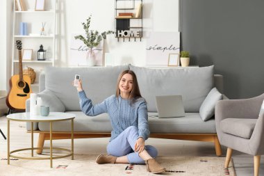 Oturma odasında klimalı, uzaktan kumandalı güzel bir kadın.