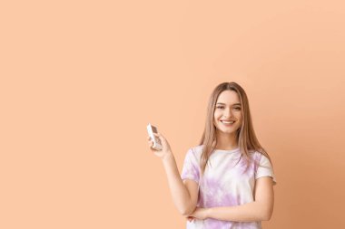 Renkli arka planda klima uzaktan kumandalı güzel bir genç kadın.