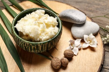 Shea yağı, fındık ve kaplıca taşlarıyla ahşap arka planda, yakın plan.