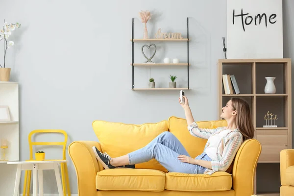 Bella Giovane Donna Con Aria Condizionata Telecomando Seduta Sul Divano — Foto Stock