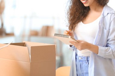 Evde paketli ve defterli genç bir kadın var.