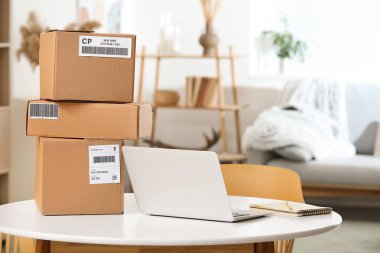 Paketler ve dizüstü bilgisayarlar evdeki masada.