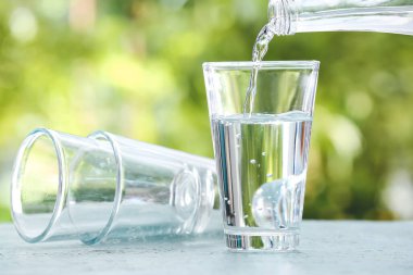 Kavanozdan bardağa temiz su dökerek.