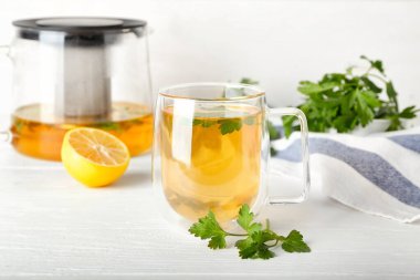 Bir fincan sıcak çay, maydanoz ve limon.