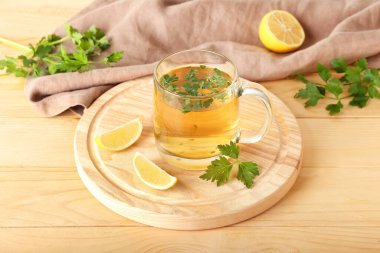 Bir fincan sıcak çay, maydanoz ve limonlu tahta arka plan.