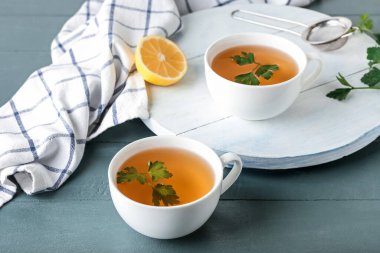 Sıcak çay, maydanoz ve limon renkli ahşap arka planda olsun.