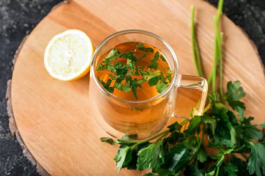 Koyu arkaplanda bir fincan sıcak çay, maydanoz ve limon olsun.