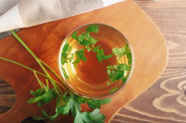 Tahta arka planda sıcak çay ve maydanoz, yakın plan.