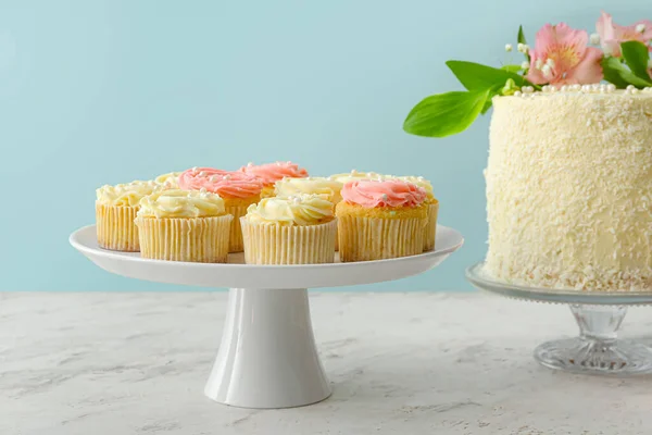 Dessertstände Mit Leckeren Cupcakes Und Kuchen Auf Farbigem Hintergrund — Stockfoto