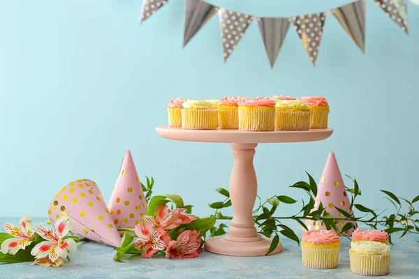 色の背景においしいカップケーキ 花やパーティー帽子とデザートスタンド — ストック写真