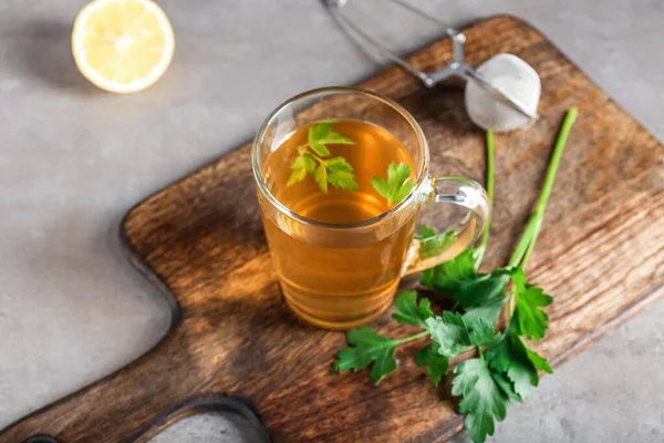 Bir fincan sıcak çay, maydanoz ve arkaplanda limon.