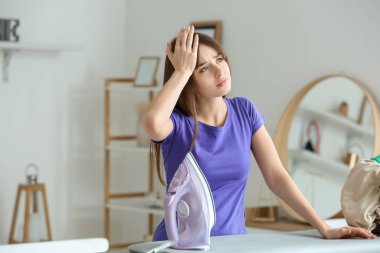 Evde çamaşırları olan yorgun genç bir kadın.