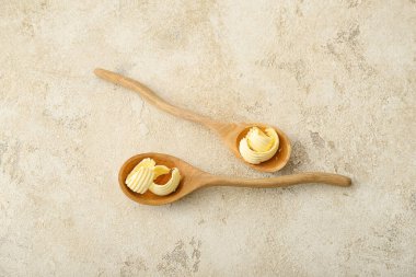 Hafif arka planda tereyağı bukleleri olan tahta kaşıklar.