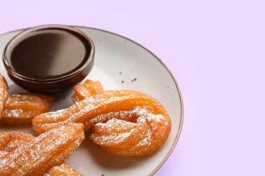 Lezzetli churros ve eritilmiş çikolata soslu bir tabak, yakın plan.