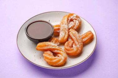 Lezzetli churros ve eritilmiş çikolata soslu bir tabak, yakın plan.