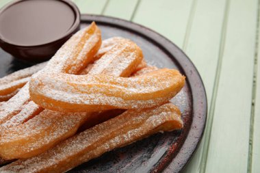 Lezzetli churros ve eritilmiş çikolata soslu, ahşap kaplama, yakın plan.