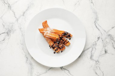 Hafif arka planda çikolataya batırılmış lezzetli churros tabağı.