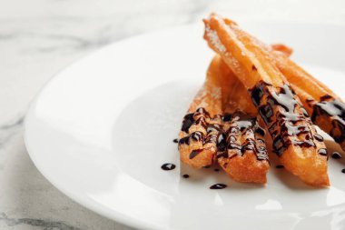 Hafif arka planda çikolataya batırılmış lezzetli churros tabağı, yakın plan.
