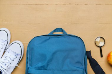 Okul çantası, ayakkabılar ve tahta arka planda büyüteç.
