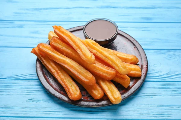 Plate Tasty Churros Melted Chocolate Sauce Color Wooden Background — Stock Photo, Image