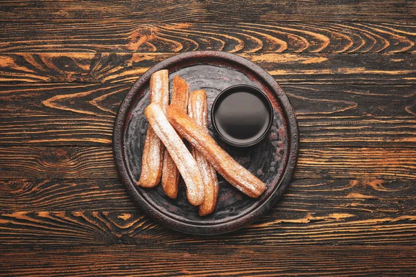 Plate Tasty Churros Melted Chocolate Sauce Wooden Background — Stock Photo, Image