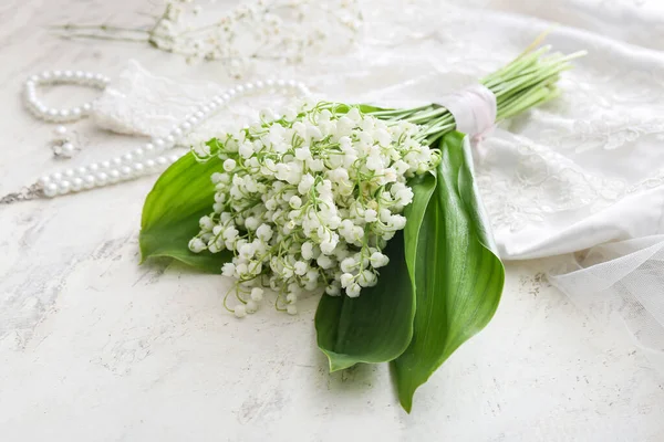 Beautiful lily-of-the-valley flowers and jewelry on light background