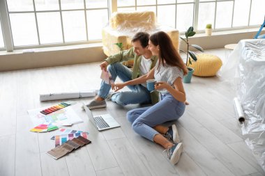 Yeni evlerinde dizüstü bilgisayar tamiratı yapan mutlu genç çift.