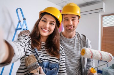 Mutlu genç çift yeni evlerinde onarım yaparken selfie çekiyor.
