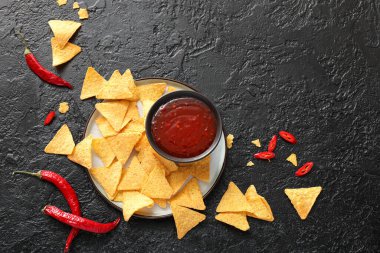 Lezzetli biber soslu kase ve koyu arkaplanda nachos.