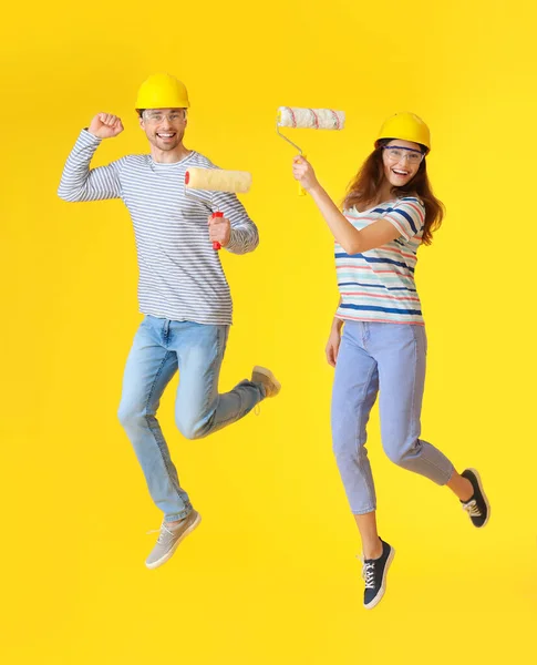 Pareja Joven Con Rodillos Pintura Saltando Sobre Fondo Color — Foto de Stock