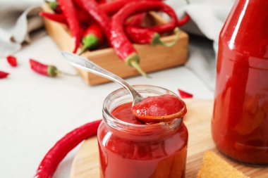 Bir kavanoz lezzetli sos ve arka planda kırmızı biber, yakın plan.