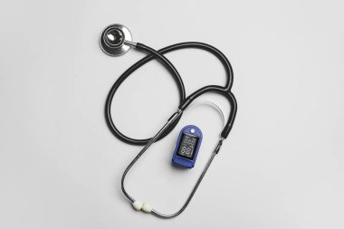 Gri arkaplanda nabız oksimetresi ve stetoskop