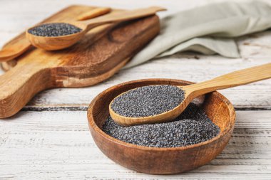 Hafif ahşap arka planda haşhaş tohumlu kase ve kaşık